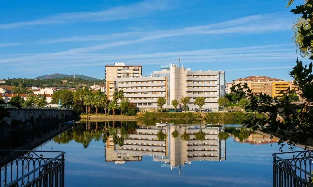 Grande Hotel Dom Dinis reflected in the Tua river beside the medieval bridge
